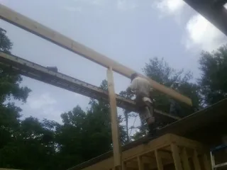 Carpenter setting a ridge beam over a new addition frame — Ice Dam Removal by Roofing Brothers in Gustine