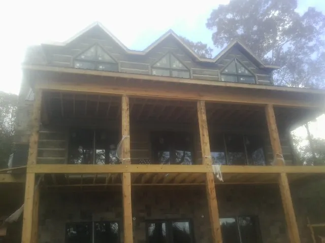 Dormers and porch framing on a large log home under construction — Roof Coating work by our crew in Gustine