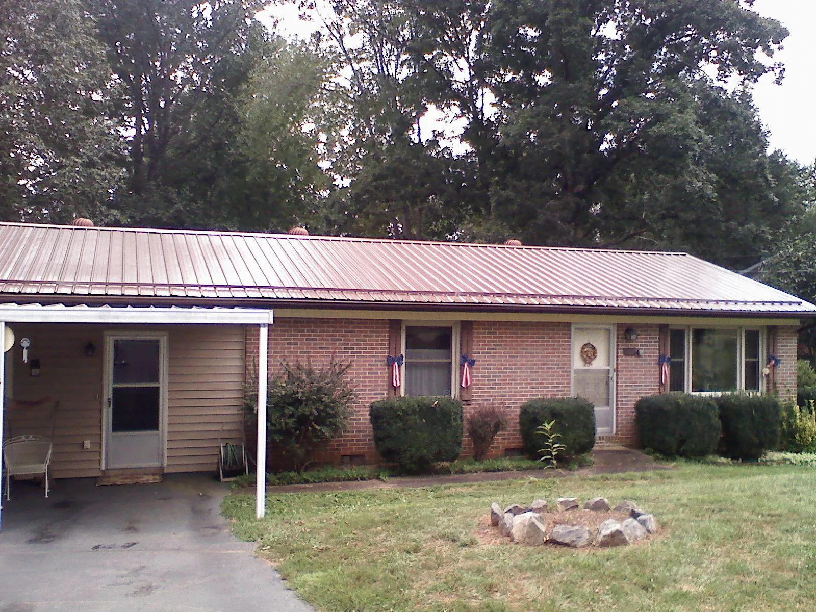 Bronze metal roof and carport on a brick ranch home — Roof Repair work by our crew in Gustine