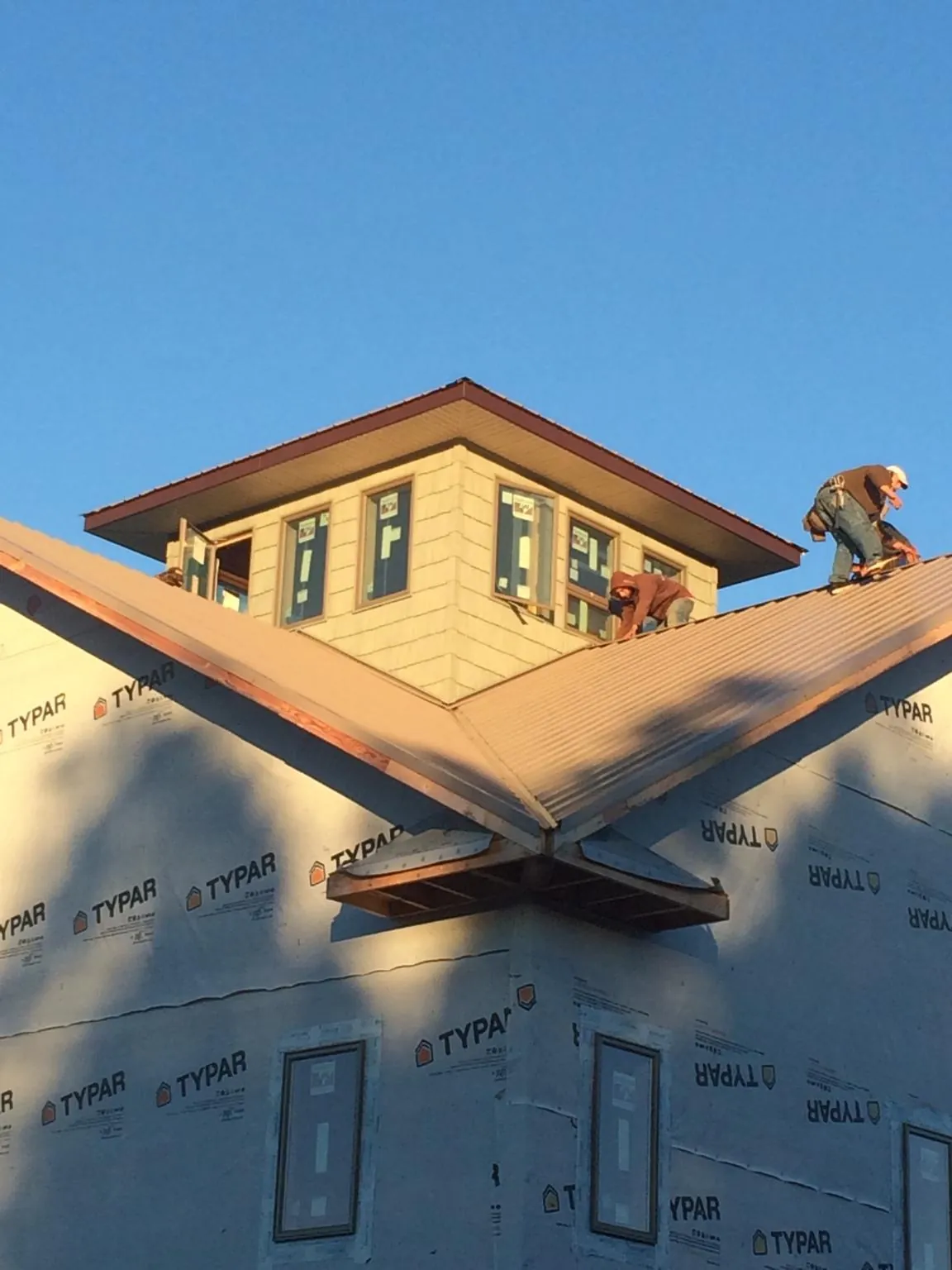Roofers working around a rooftop cupola on a new metal roof at sunset — Roof Waterproofing in Gustine by Roofing Brothers